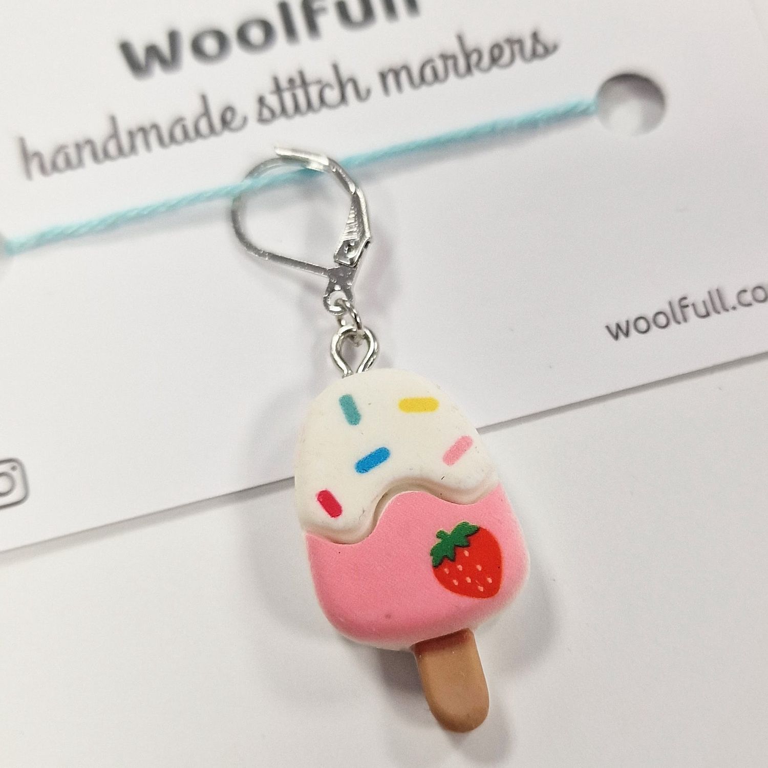A pink and white ice lolly shaped stitch marker.