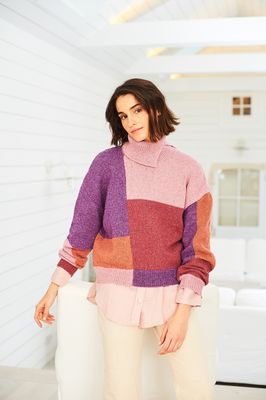 A woman is wearing a colour block knitted sweater in shades of purple, pink and orange.