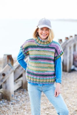 A woman is wearing a variegated knitted tank top in shades of green, blue, teal and purple.