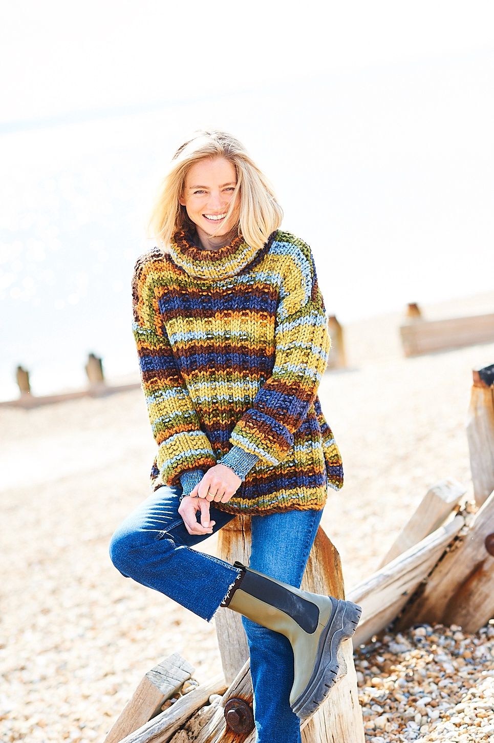 A woman is wearing a variegated knitted sweater in shades of green, blue, orange and brown.