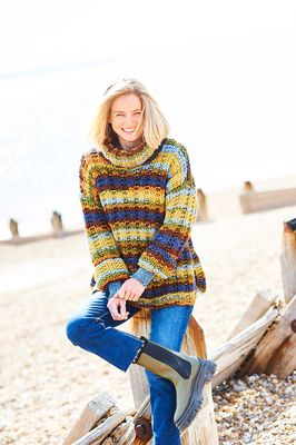 A woman is wearing a variegated knitted sweater in shades of green, blue, orange and brown.