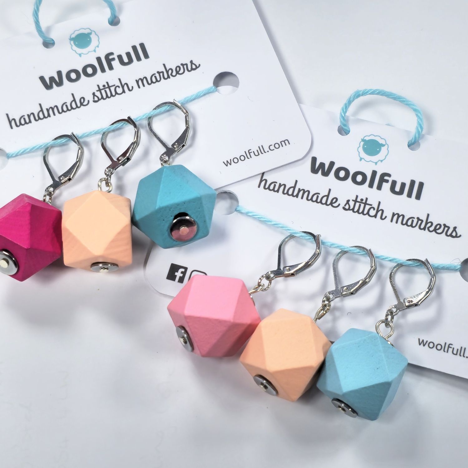 2 packs of stitch markers, each with 3 brightly coloured wooden geo stitch markers.