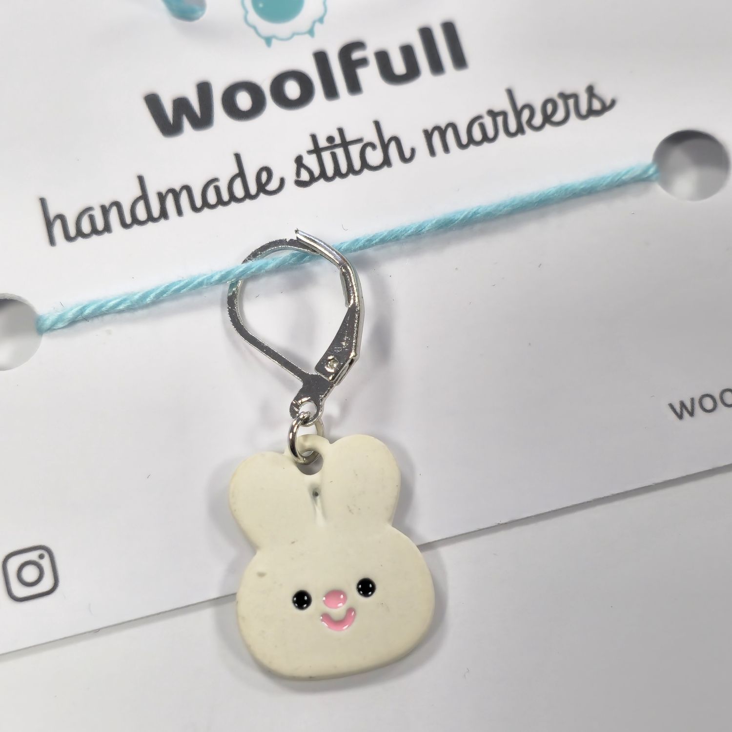 A cream cartoon rabbit face stitch marker.