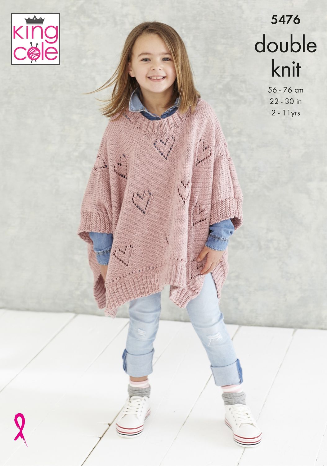 A girl is wearing a pink knitted poncho with lace heart detail on the body.