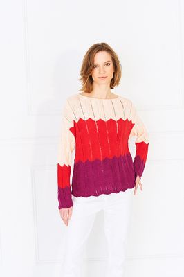 A woman is wearing a knitted ripple sweater in peach, red and purple.