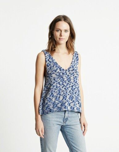 A woman is wearing a knitted tank top in a variegated blue and white yarn.