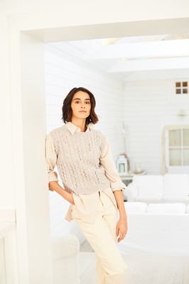 A woman is wearing a round neck knitted tank top in pale grey.