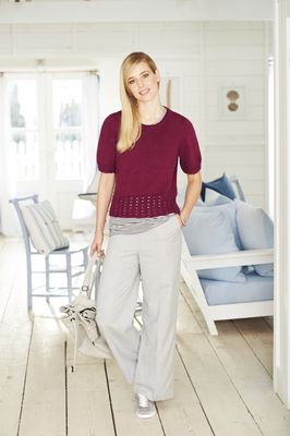 A woman is wearing a burgundy red knitted top.