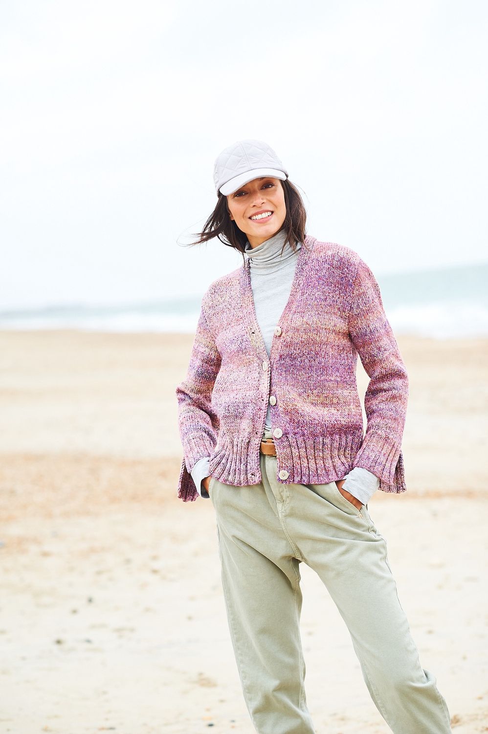 A woman is wearing a knitted cardigan in shades of pink.
