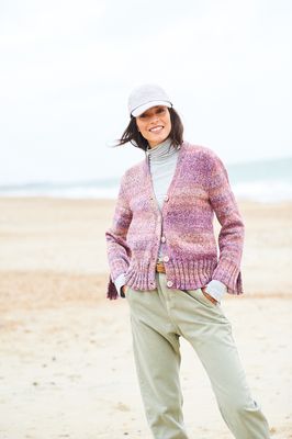 A woman is wearing a knitted cardigan in shades of pink.