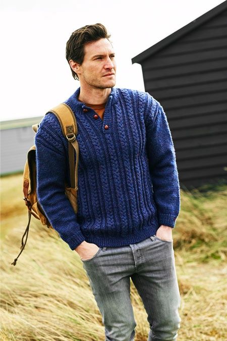 A man is wearing a dark blue sweater with a cable design on the front.