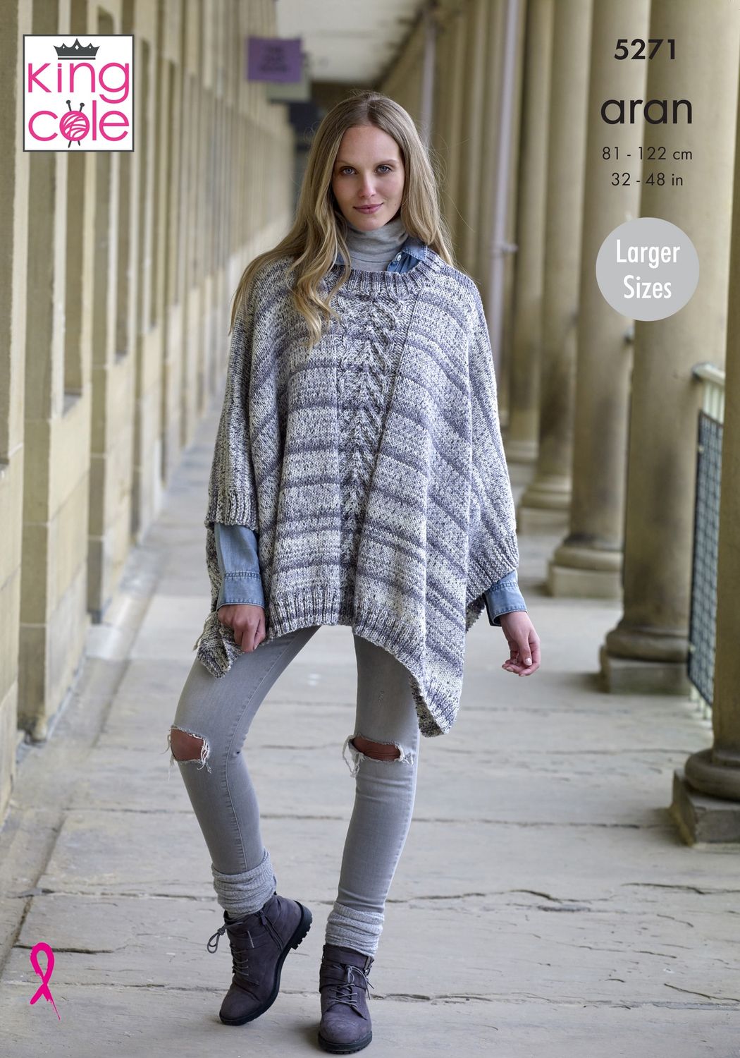 A woman is wearing a knitted poncho in a variegated blue and grey yarn.
