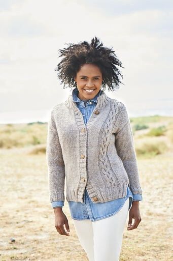 A woman is wearing a beige knitted cardigan with cable on one side.