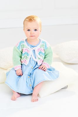 A baby is wearing a knitted ripple cardigan in green, blue, cream and pink.