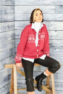A woman is wearing a dark pink knitted cardigan with cream fair isle stars.