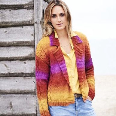 A woman is wearing a knitted cardigan in a variegated pink, orange and yellow yarn.