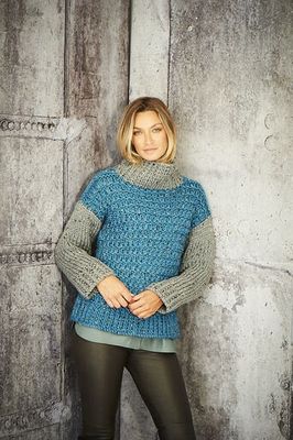 A woman is wearing a dark blue knitted sweater with grey sleeves and colllar.