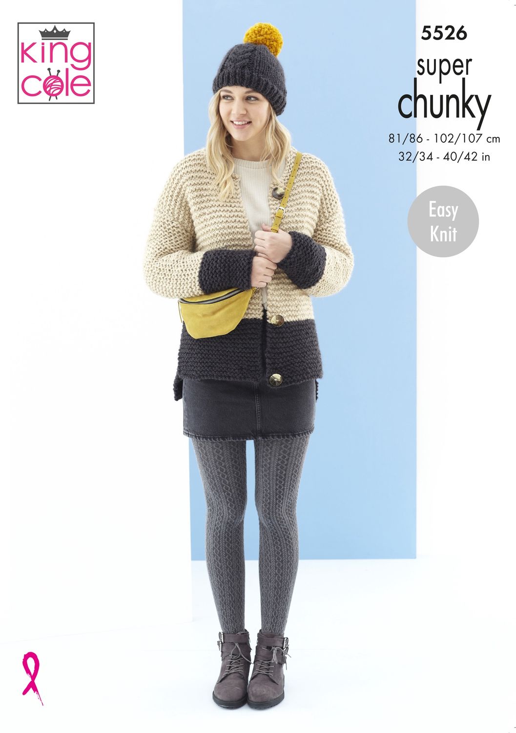 A woman is wearing a beige and grey knitted cardigan and a grey and mustard knitted hat.