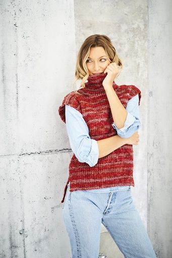 A woman is wearing a knitted top in a variegated dark pink yarn.