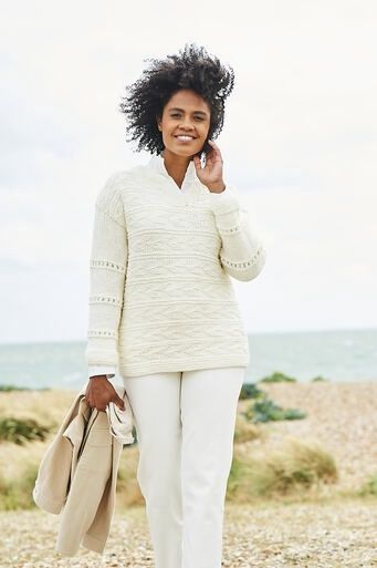 A woman is wearing a cream knitted sweater.