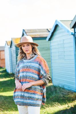 A woman is wearing a knitted poncho in shades of blue and orange.