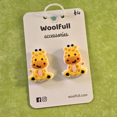 A green background with a pair of giraffe shaped point protectors mounted on a white card.