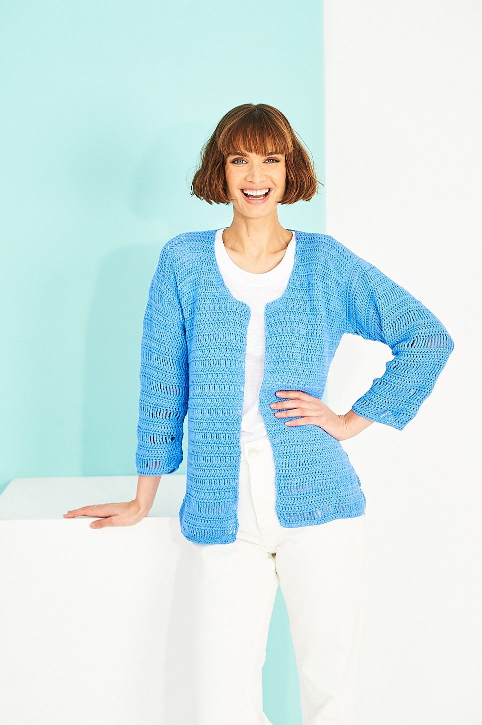 A woman is wearing a blue crocheted cardigan.