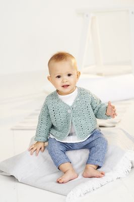 A baby is wearing a sage green crocheted cardigan.
