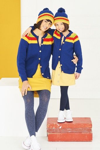 A woman and a girl are wearing matching navy blue knitted cardigan with yellow, green and red stripes.