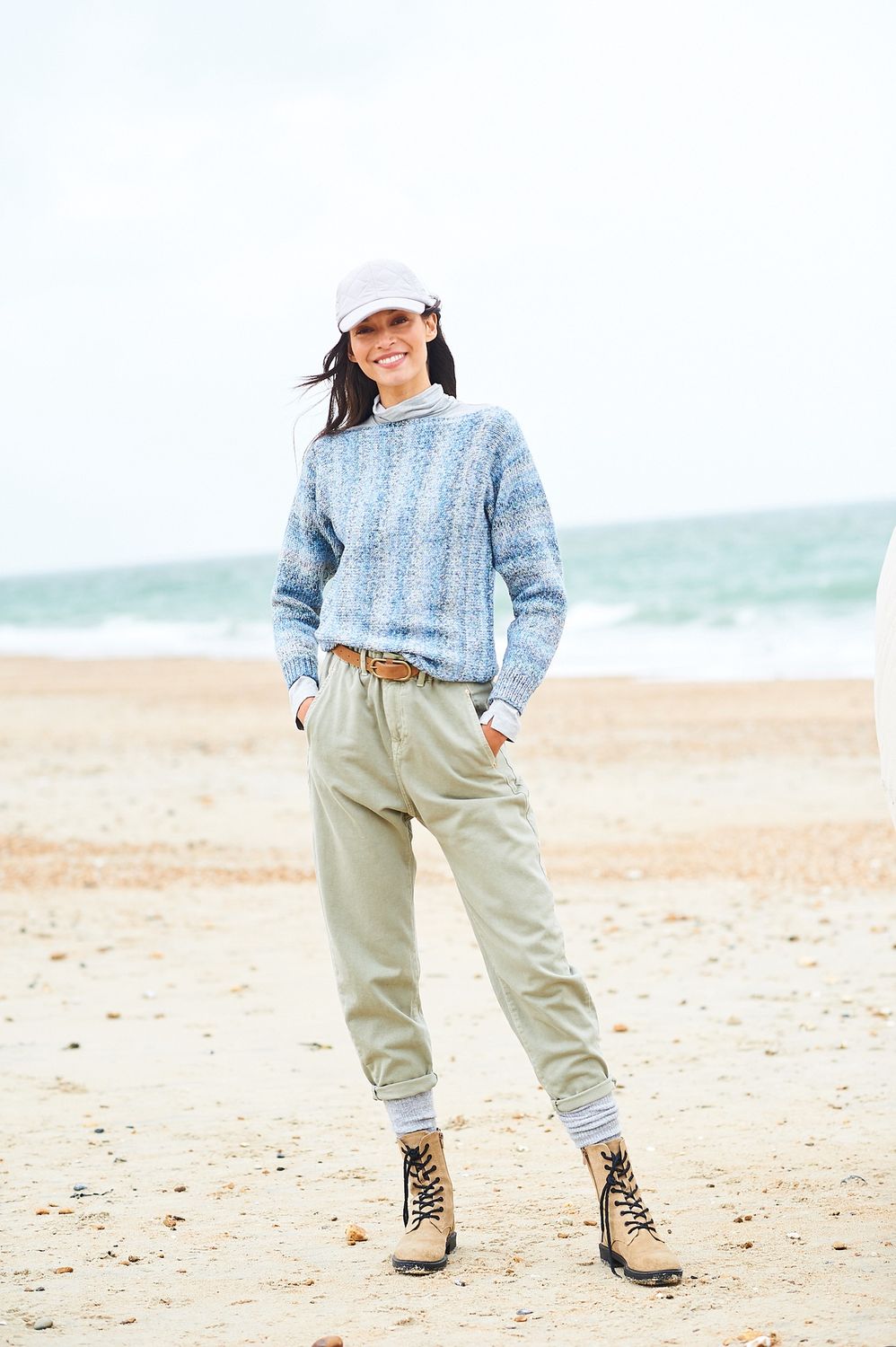 A woman is wearing a knitted sweater in shades of blue.
