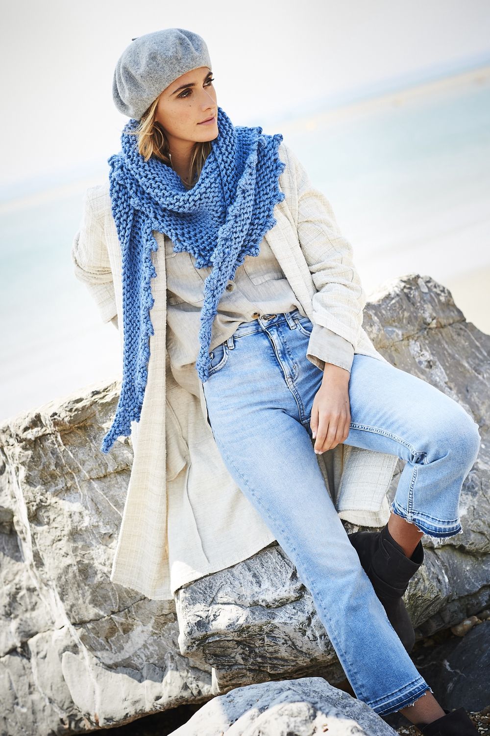 A woman is wearing a blue knitted shawl.