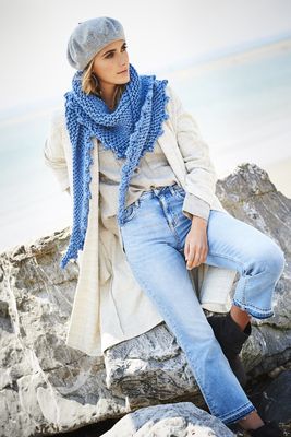 A woman is wearing a blue knitted shawl.
