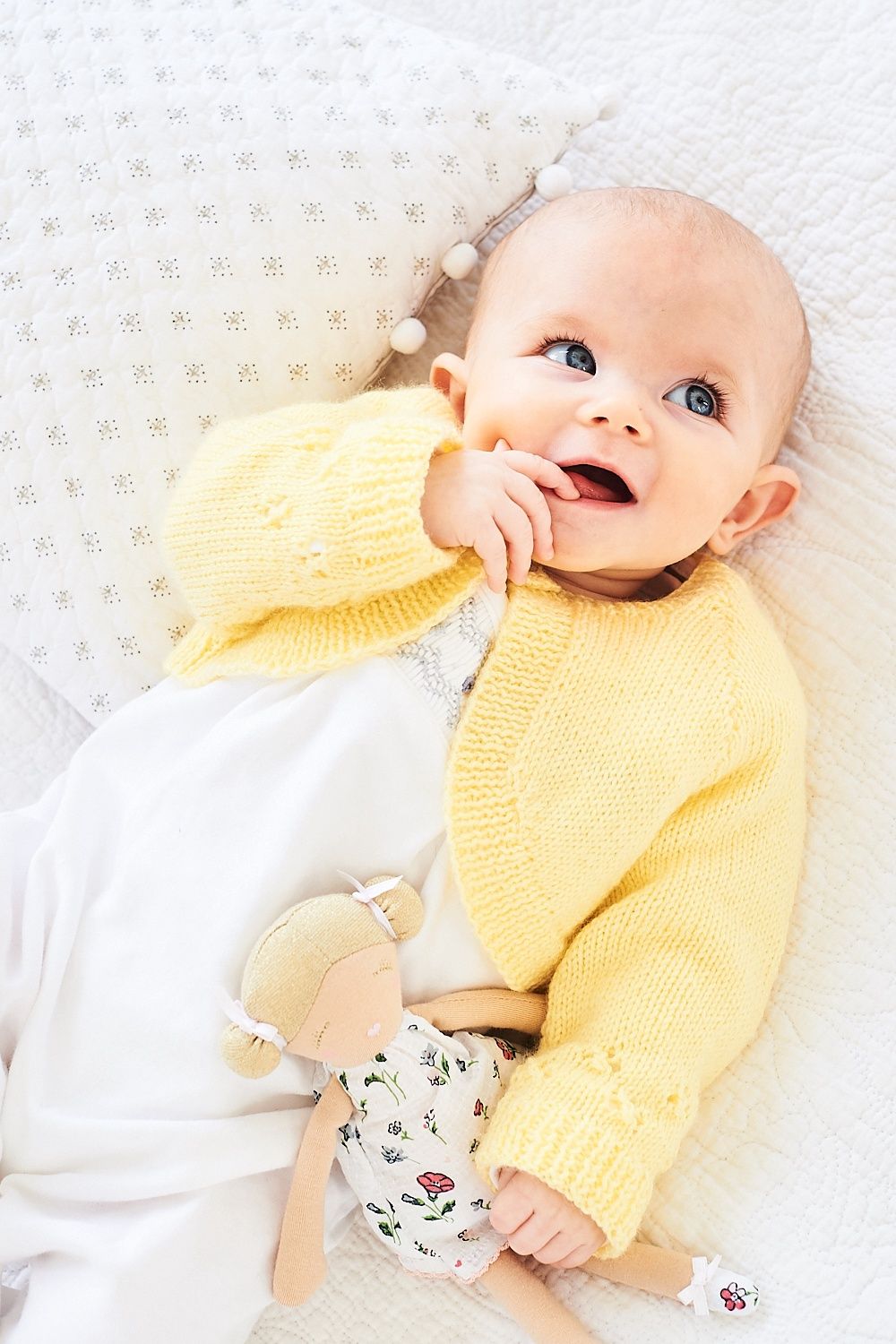 A baby is wearing a yellow knitted cardigan.