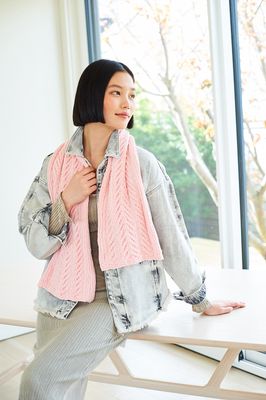A woman is wearing a pink knitted scarf.