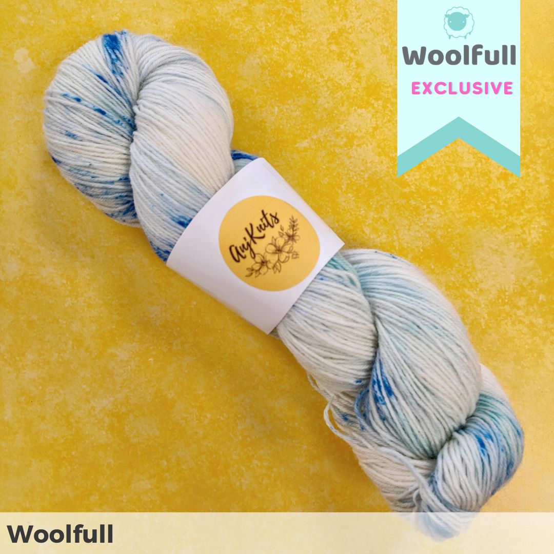 A skein of yarn in cream with blue speckles.
