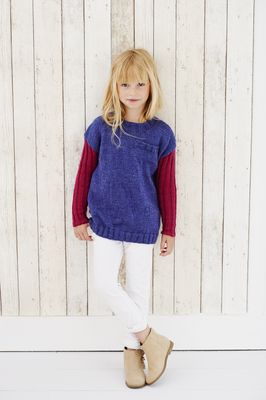 A girl is wearing a blue knitted sweater with dark pink sleeves.