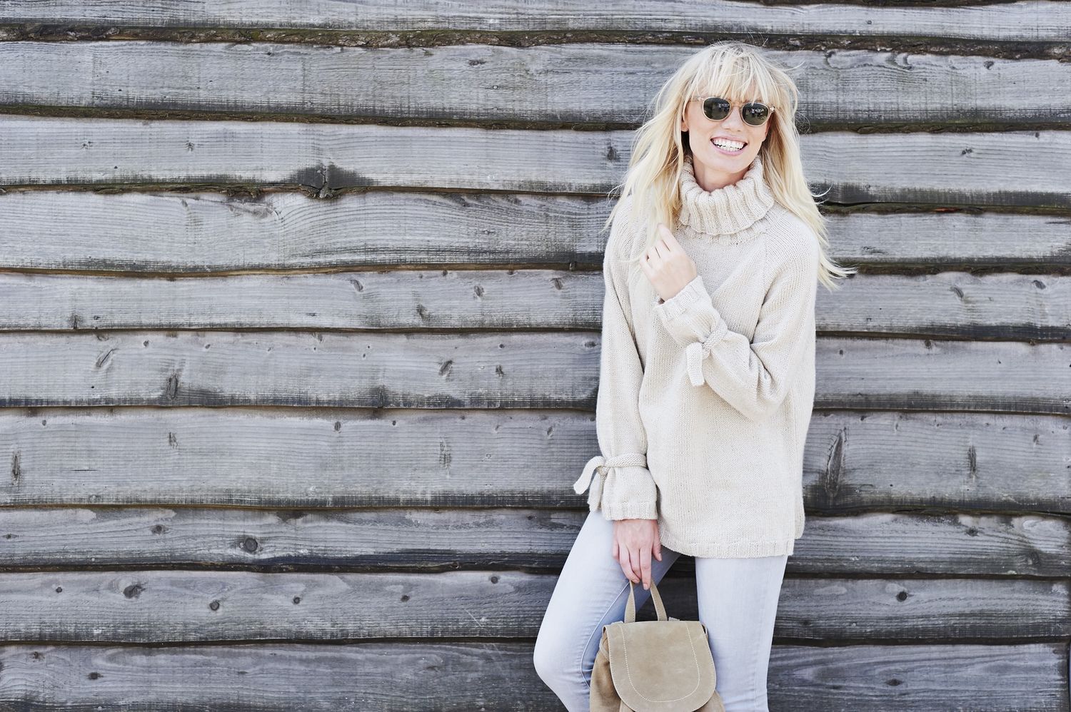 A woman is wearing a cream knitted sweater.