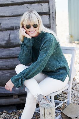 A woman is wearing a dark green knitted sweater.