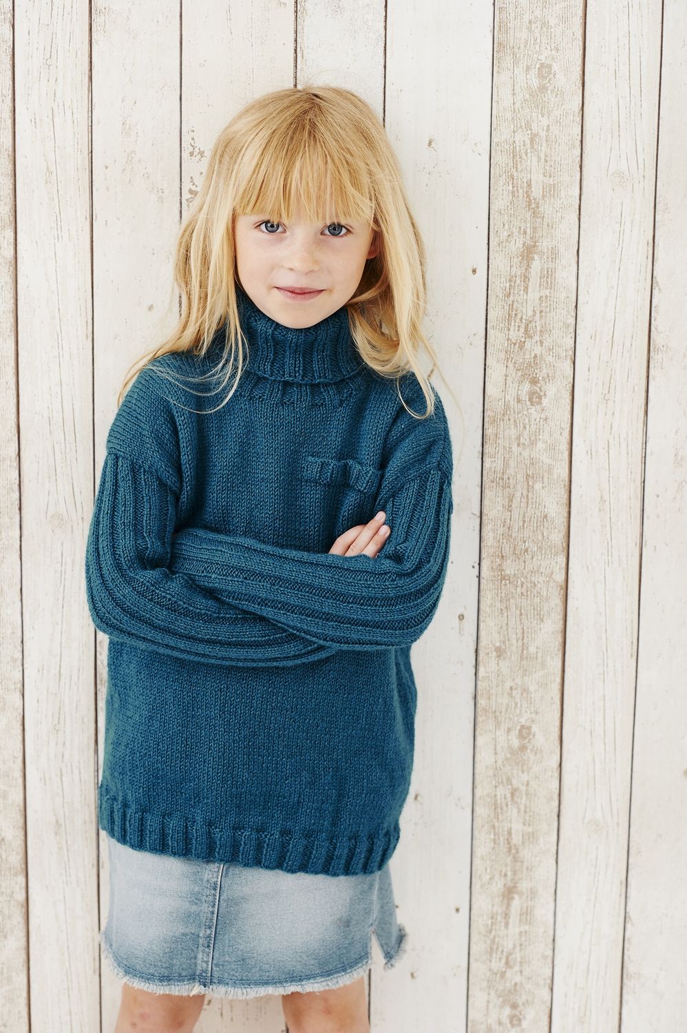 A girl is wearing a dark teal knitted sweater.