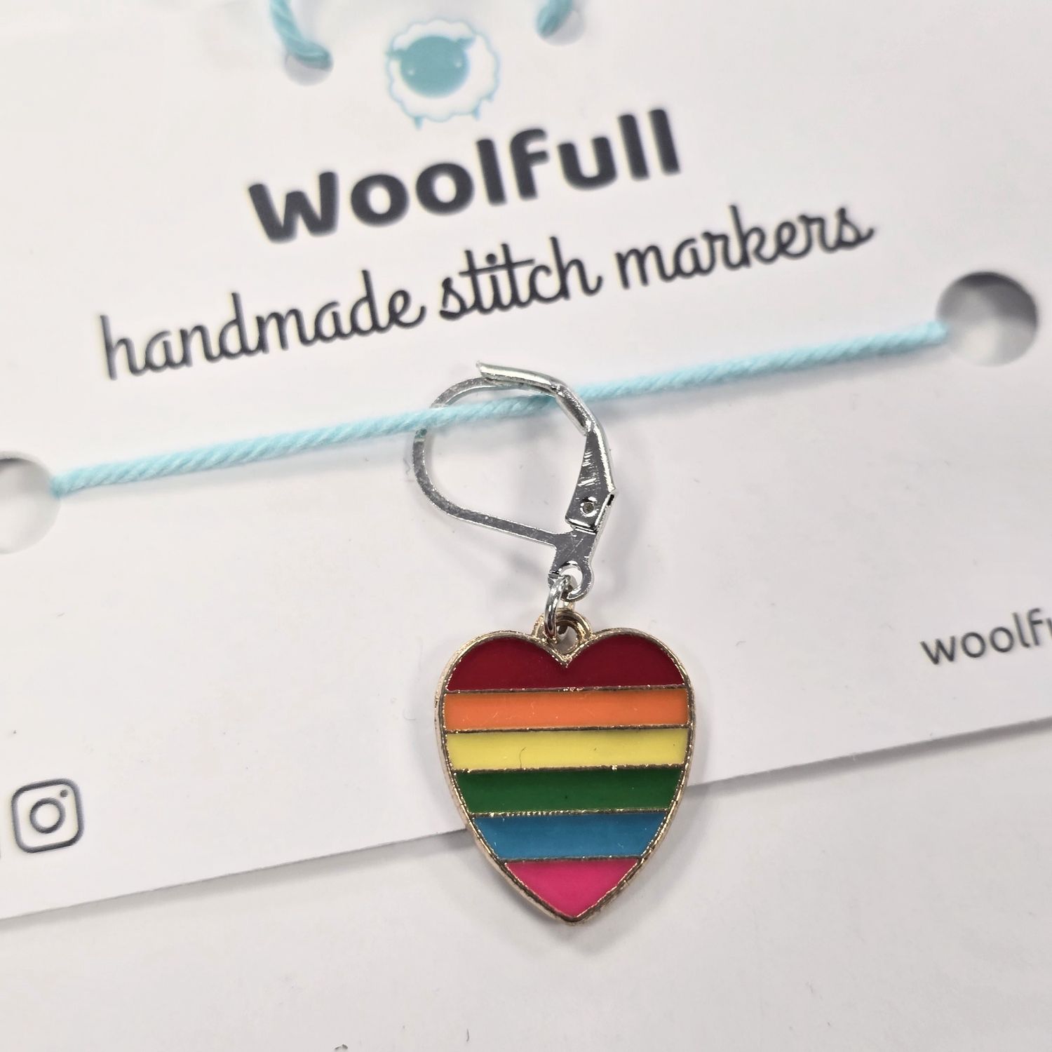A rainbow coloured heart shaped stitch marker.