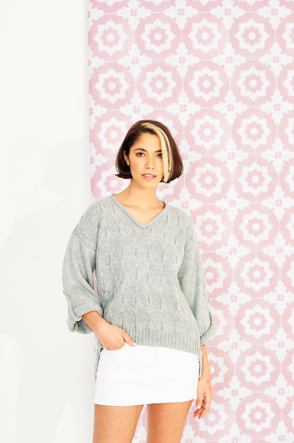 A woman is wearing a grey knitted sweater.