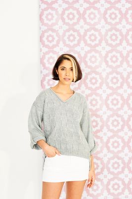 A woman is wearing a grey knitted sweater.