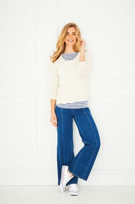 A woman is wearing a cream knitted sweater.