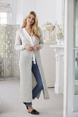 A woman is wearing a long pale grey knitted cardigan.