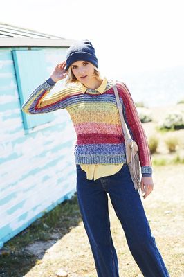 A woman is wearing a knitted sweater in red, coral, yellow, green and blue stripes.