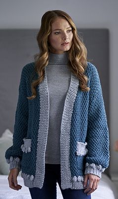A woman is wearing a blue and silver knitted cardigan.