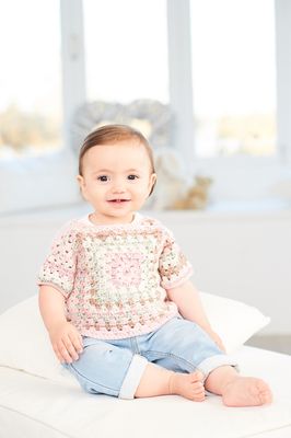 A baby is wearing a variegated pink crocheted top.
