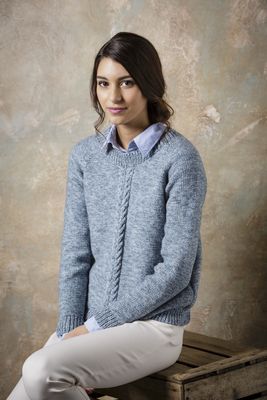 A woman is wearing a pale blue knitted sweater with cable detail down the front.