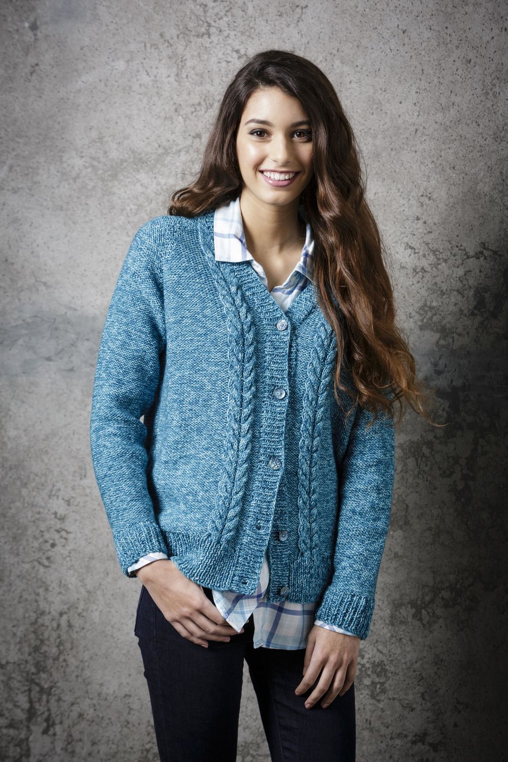 A woman is wearing a bright blue knitted cardigan with cable detail down the front.