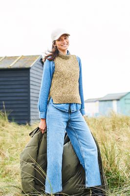 A woman is wearing a knitted tank top in a variegated green yarn.